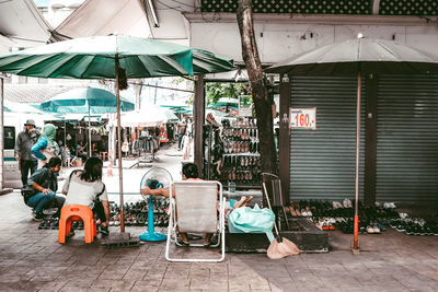 People sitting on chairs at street in city