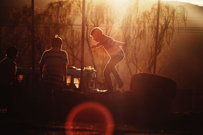 Boys playing in field during sunset