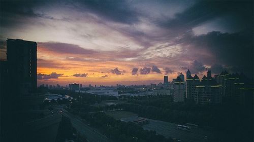 Cityscape against cloudy sky at sunset