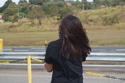 Rear view of woman standing on road