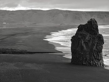 Rock formation on beach against sky