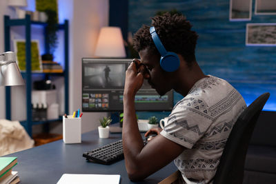 Rear view of woman using mobile phone while sitting at home
