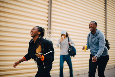 Happy teenage girl walking with friends against shutter