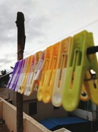 Low angle view of clothespins hanging on clothesline against sky