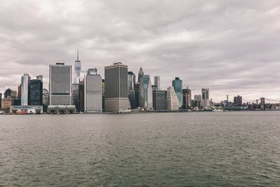 Sea by modern buildings against sky in city