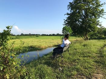 Man sitting on seat in field against sky