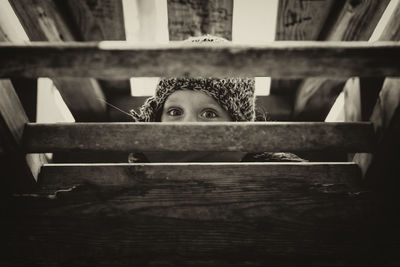 Portrait of a boy peeking through wooden table