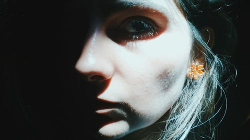 Close-up portrait of serious young woman against black background
