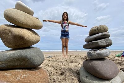 Stack of pebbles on rock against sky