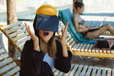 Shocked woman using virtual reality simulator on lounge chair at beach