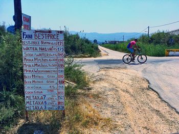 Man cycling on street against clear sky