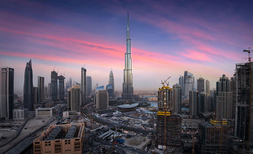 High angle view of modern cityscape against cloudy sky during sunset