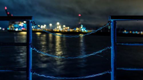 Illuminated bridge over river in city at night