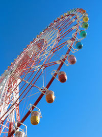 Low angle view of ferris wheel against clear blue sky