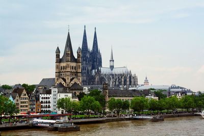 View of temple by river against cloudy sky