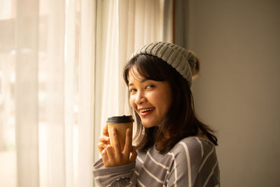 Portrait of smiling young woman holding coffee cup