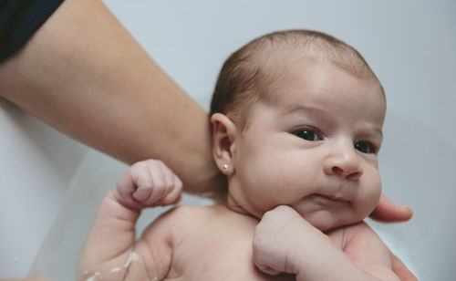 Cropped hand of mother bathing son in bathtub at home