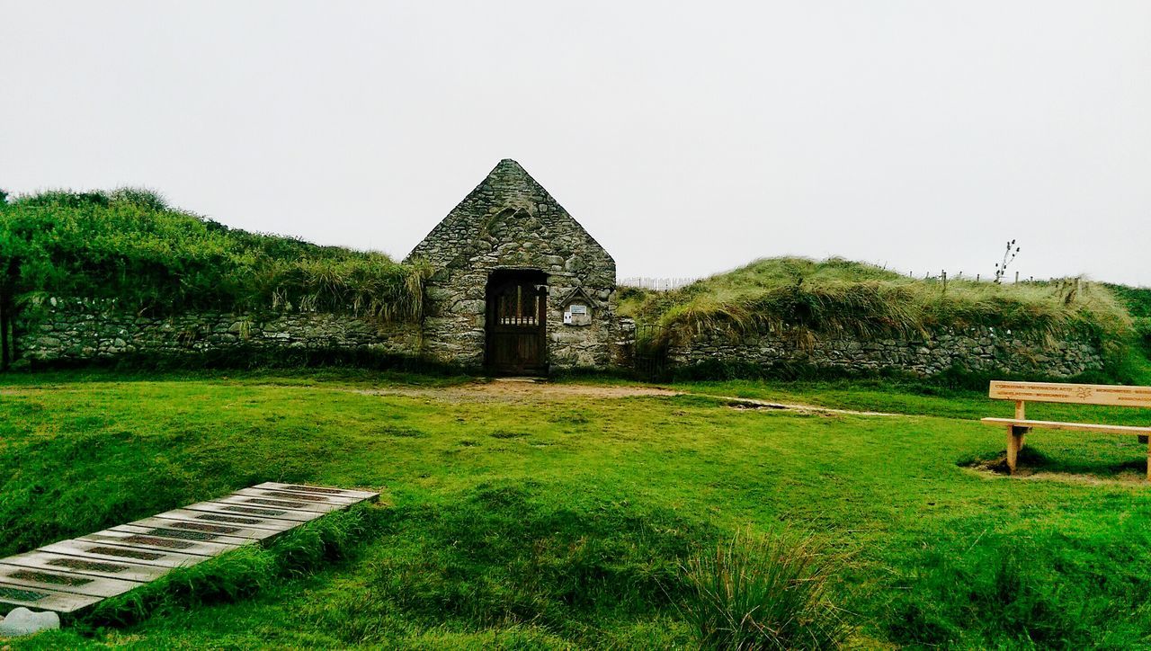 grass, built structure, tranquil scene, architecture, tranquility, clear sky, scenics, green color, non-urban scene, plant, outdoors, green, solitude, countryside, day, sky, footpath, beauty in nature, rural scene, growth, nature, remote, arch, chapel, lush foliage, no people