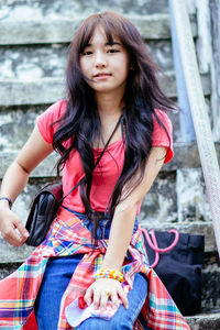 Portrait of young woman sitting on railing