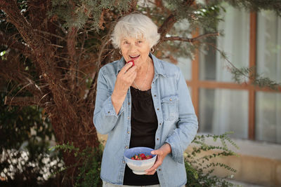 Elderly woman holding a bowl of ripe strawberries