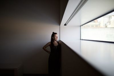 Woman looking through window at home