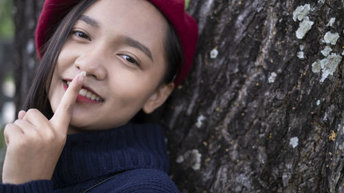 Close-up portrait of a young woman with tree trunk