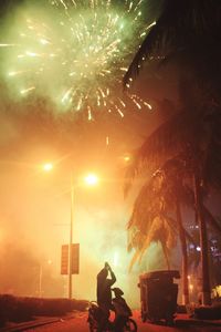 Man photographing firework display on street at night