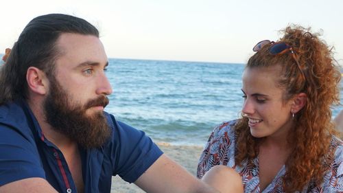Portrait of smiling young couple on beach against sky