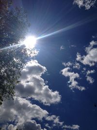 Low angle view of sun shining through clouds