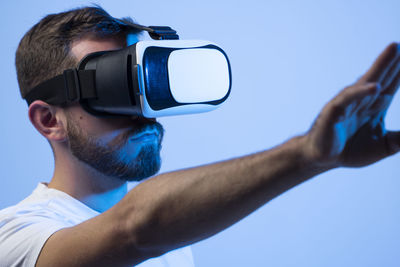 Low angle view of young man photographing against blue background