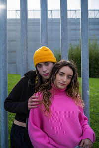 Portrait of smiling young woman standing against fence