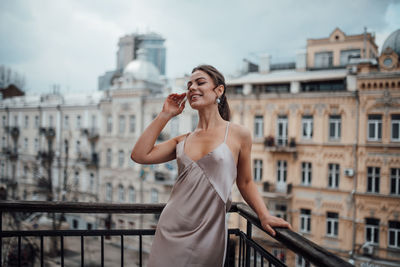 Full length of woman standing against railing in city