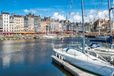 Boats moored at harbor against buildings in city