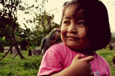 Close-up of girl with bird on shoulder at park