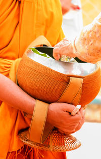 Midsection of man holding orange while standing at temple