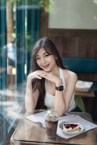 Portrait of smiling young woman using smart phone at restaurant