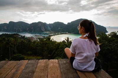 Rear view of woman sitting at observation point against sea