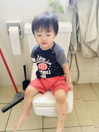 Cute boy sitting on seat at home