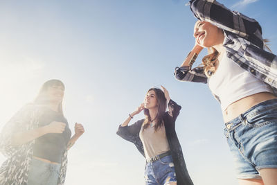 Low angle view of women standing against sky