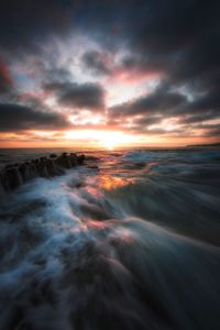 Scenic view of sea against dramatic sky during sunset