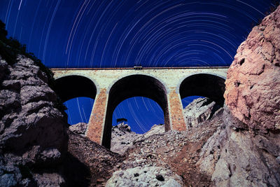 Low angle view of arch bridge against star trails