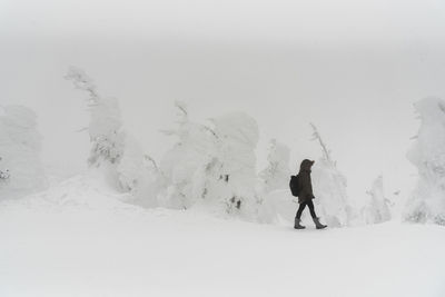 Full length of woman walking on snow covered landscape