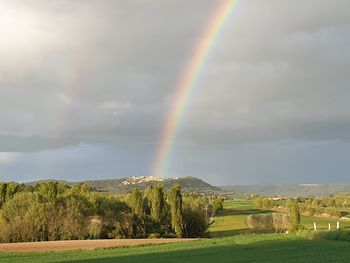 Scenic view of rainbow over landscape against sky