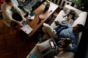 High angle view of family using various technologies in living room at home