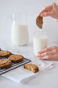 Woman's hand dipping homemade cookies into a glass of milk