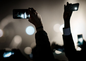 Cropped image of hands photographing through smart phones at concert
