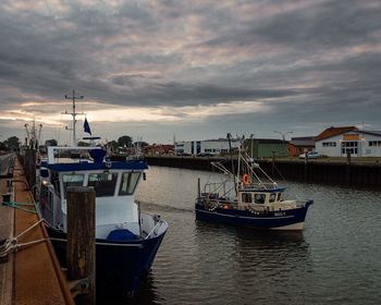 Boats moored at harbor against sky during sunset