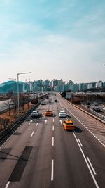 Vehicles on road against sky in city