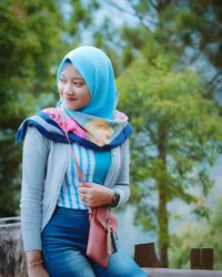 Full length of a smiling young woman standing against trees