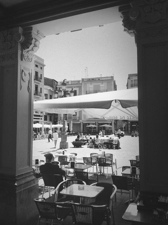 architecture, built structure, building exterior, clear sky, chair, city, table, men, incidental people, day, restaurant, street, person, sidewalk cafe, transportation, window, large group of people, city life, mode of transport